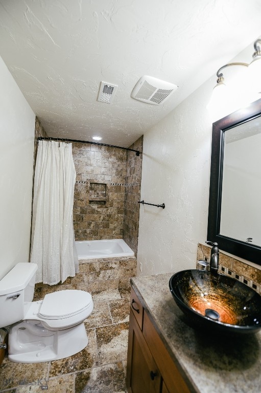 full bathroom featuring vanity, toilet, a textured ceiling, and shower / tub combo with curtain