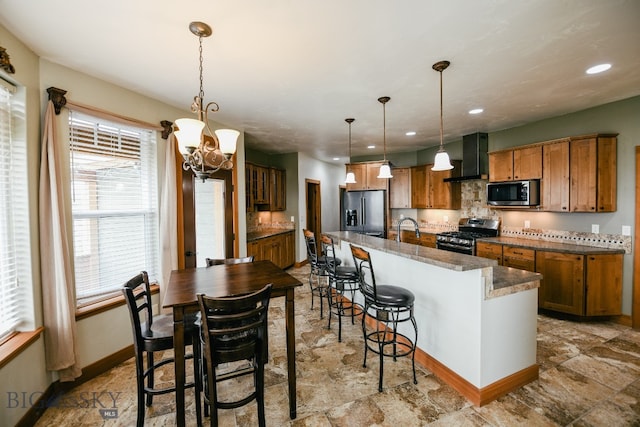 kitchen featuring pendant lighting, a kitchen island with sink, an inviting chandelier, stainless steel appliances, and premium range hood