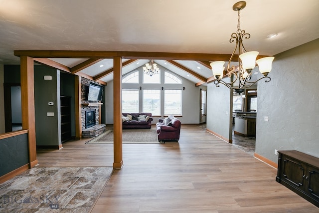 interior space featuring vaulted ceiling with beams, light hardwood / wood-style floors, a fireplace, and a chandelier