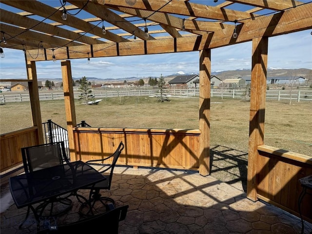 view of patio with fence, a pergola, and a rural view