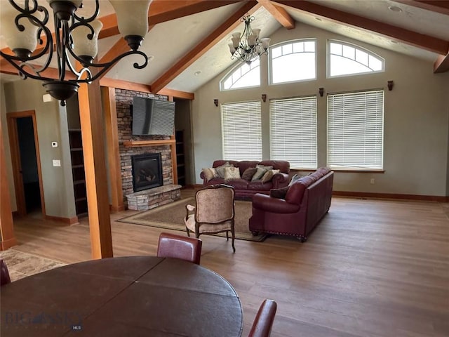 living area featuring a stone fireplace, lofted ceiling with beams, an inviting chandelier, and wood finished floors