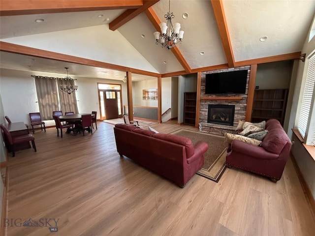 living room featuring high vaulted ceiling, light wood-type flooring, a fireplace, a notable chandelier, and beam ceiling