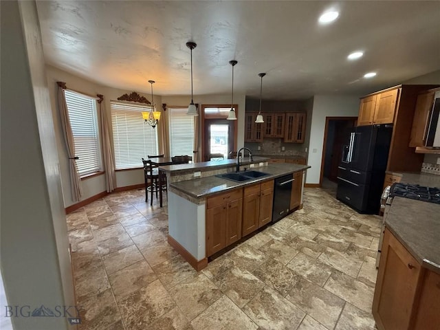 kitchen featuring black appliances, baseboards, a sink, and a center island with sink