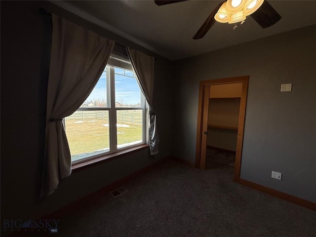 unfurnished bedroom with visible vents, a ceiling fan, a walk in closet, baseboards, and carpet flooring