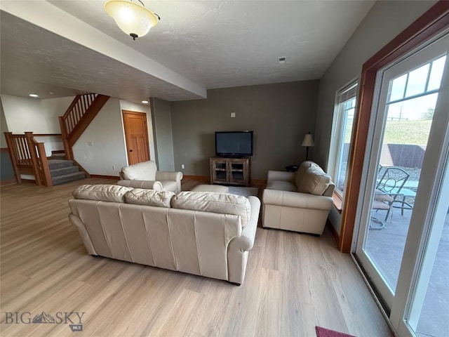 living area featuring stairs, light wood-style floors, and baseboards