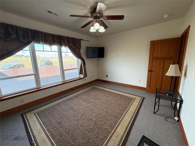interior space with carpet floors, visible vents, a ceiling fan, and baseboards