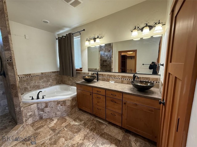 full bathroom featuring a garden tub, stone tile flooring, a sink, and double vanity