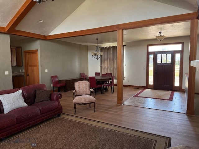 living area featuring vaulted ceiling, baseboards, wood finished floors, and an inviting chandelier