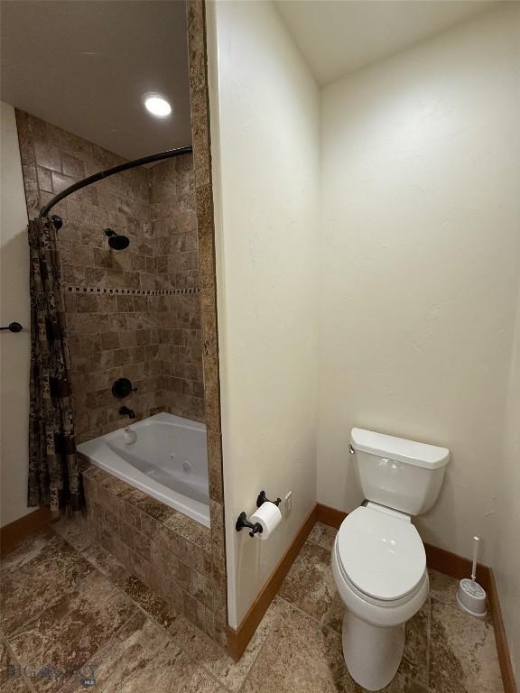full bathroom with tiled shower / bath combo, baseboards, and toilet