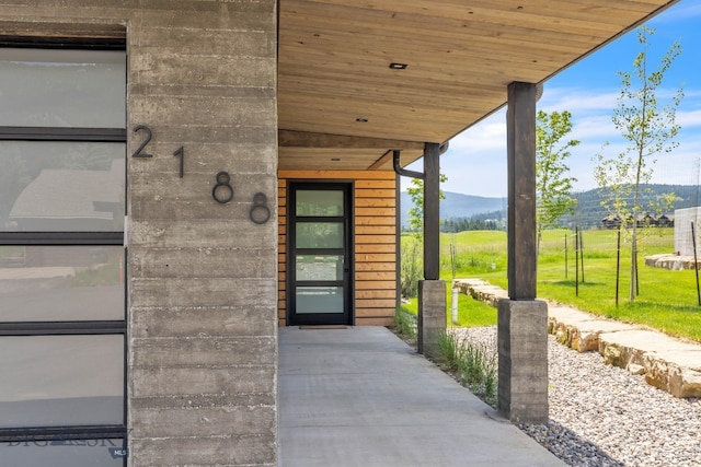 doorway to property featuring a mountain view and a lawn