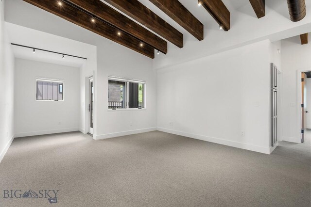 unfurnished room with vaulted ceiling with beams, carpet, and rail lighting