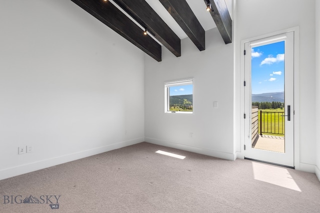 unfurnished room with beamed ceiling, track lighting, and carpet flooring