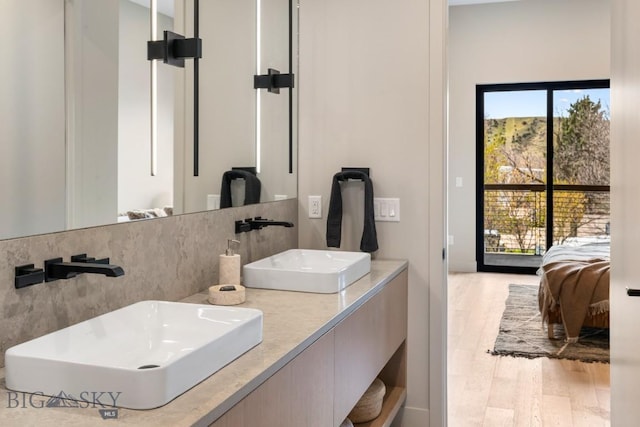 bathroom featuring a sink, ensuite bath, and wood finished floors