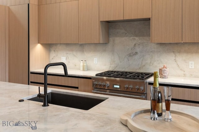 kitchen featuring tasteful backsplash, high end stainless steel range oven, a sink, and modern cabinets