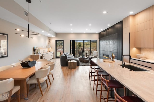 interior space featuring light wood-type flooring, a large fireplace, visible vents, and recessed lighting