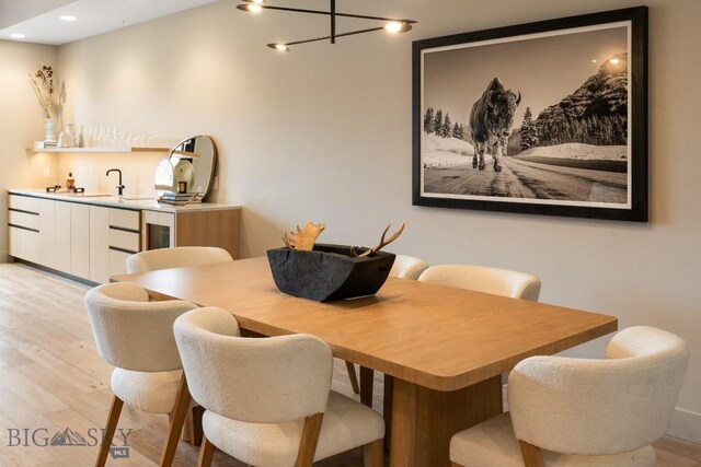 dining space with light wood-style floors, wet bar, and recessed lighting