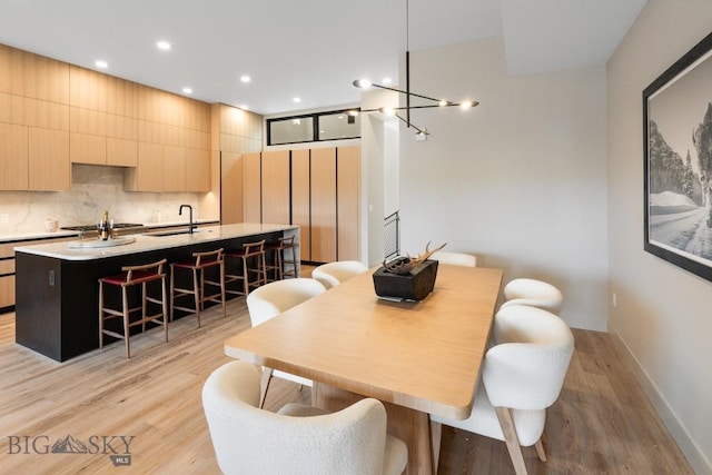 dining area featuring baseboards, light wood finished floors, a notable chandelier, and recessed lighting