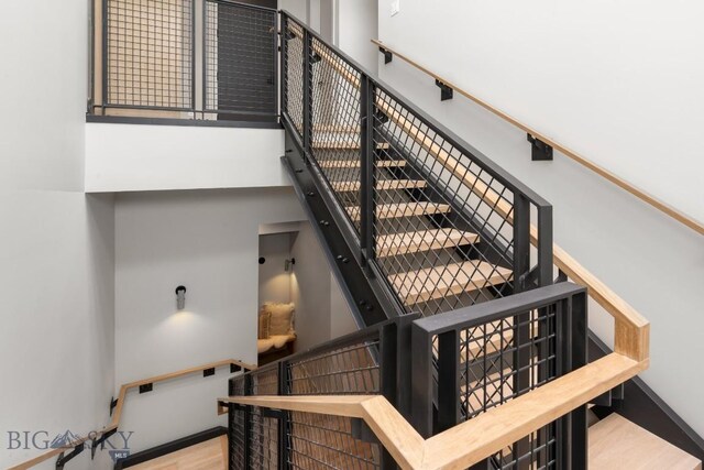 stairs featuring a towering ceiling and wood finished floors