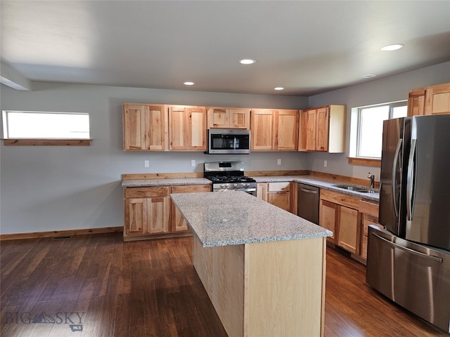 kitchen featuring appliances with stainless steel finishes, sink, light stone counters, a center island, and dark wood-type flooring