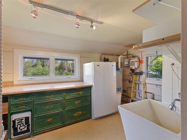 kitchen with sink, white refrigerator, track lighting, green cabinetry, and vaulted ceiling