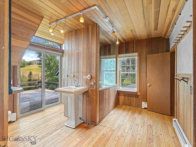 entryway with a baseboard radiator, rail lighting, wooden ceiling, and wood walls