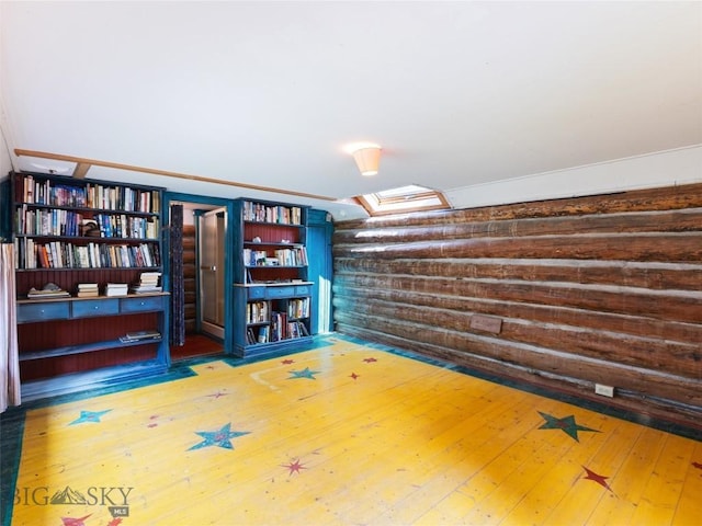 interior space featuring hardwood / wood-style flooring, a skylight, and wood walls