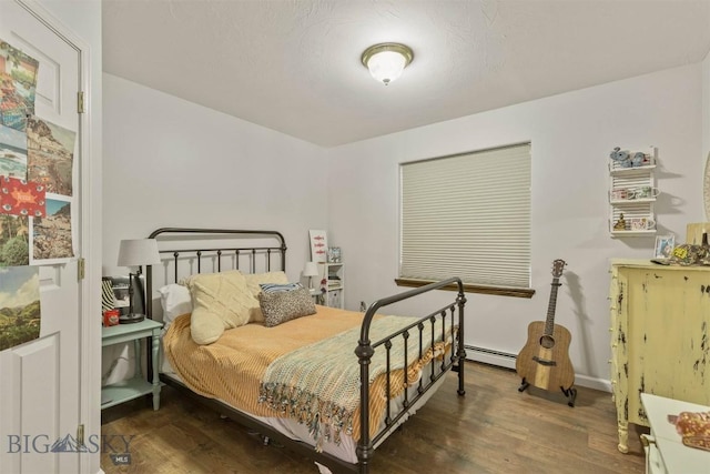 bedroom featuring a baseboard heating unit and dark wood-type flooring