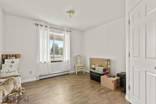 living area with a baseboard heating unit and hardwood / wood-style floors