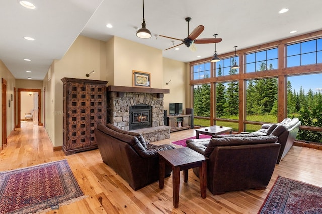 living room featuring a fireplace, a high ceiling, light wood-type flooring, and ceiling fan