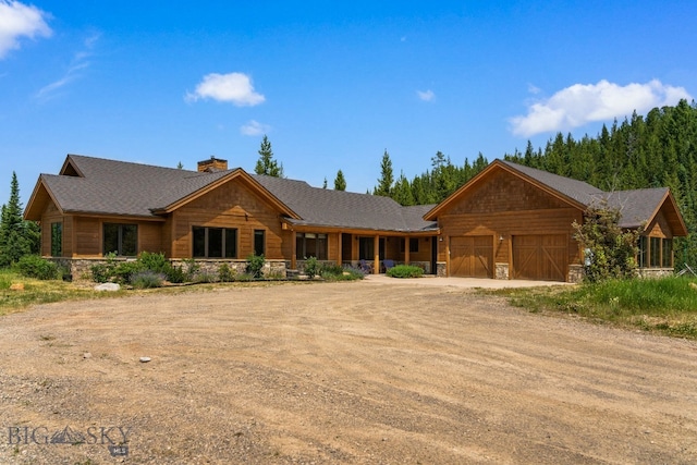 220 Watershed Rd, Big Sky, MT 59716 - log cabin with stone siding, dirt driveway, an attached garage, and a chimney