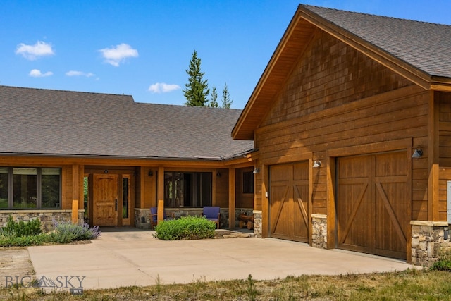 220 Watershed Rd, Big Sky, MT 59716 - view of front of property featuring driveway, stone siding, roof with shingles, and an attached garage