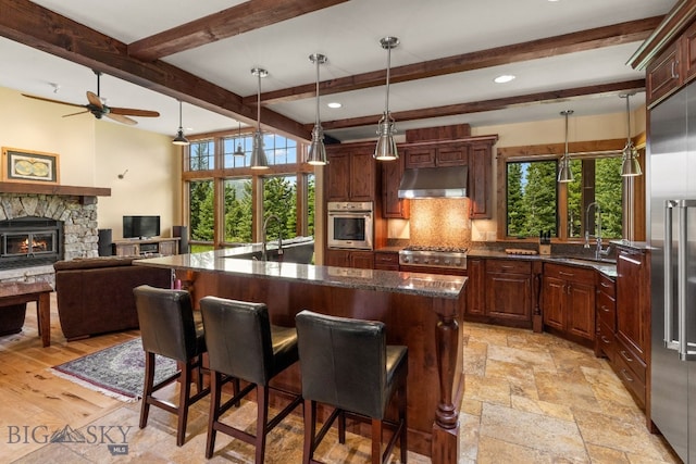 kitchen featuring a fireplace, a wealth of natural light, a center island, and stainless steel appliances