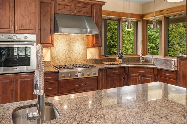 kitchen featuring sink, stainless steel appliances, dark stone countertops, and range hood