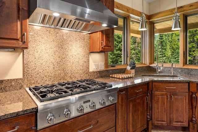 kitchen featuring sink, stainless steel gas cooktop, dark stone countertops, and range hood