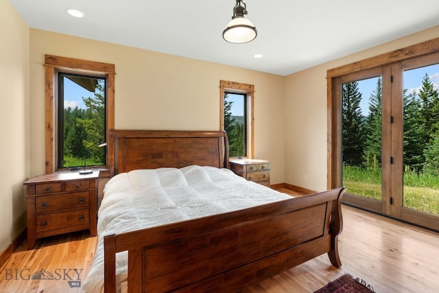 bedroom with light hardwood / wood-style floors, access to outside, and multiple windows