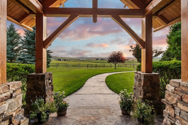 patio terrace at dusk featuring a rural view and a yard