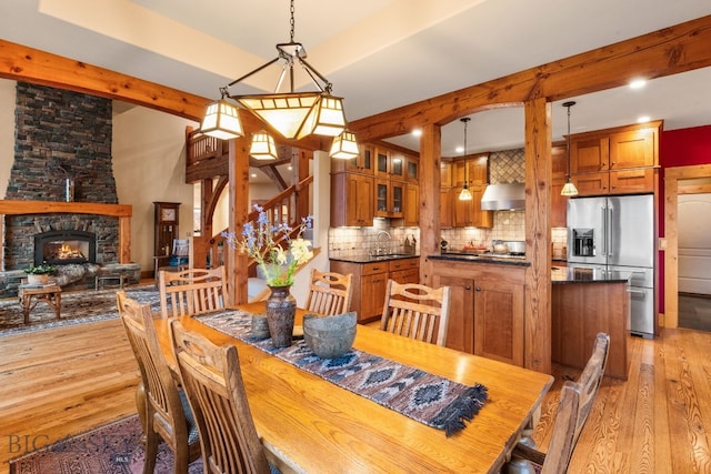 dining space featuring light hardwood / wood-style flooring, sink, and a stone fireplace