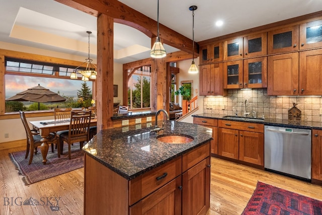 kitchen featuring hanging light fixtures, sink, a kitchen island with sink, dishwasher, and light wood-type flooring