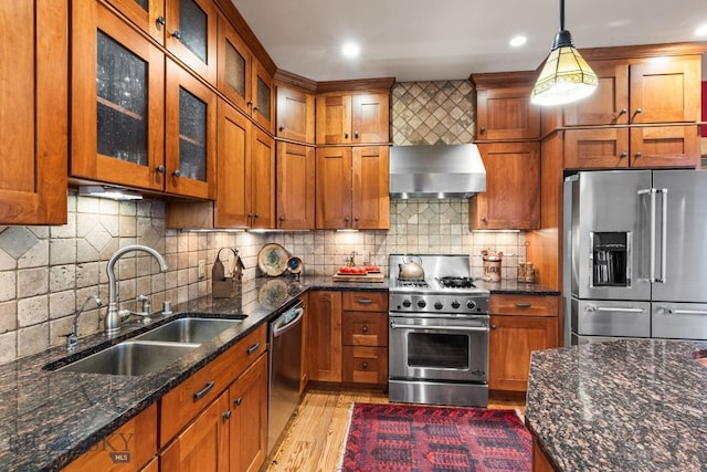 kitchen with pendant lighting, sink, tasteful backsplash, wall chimney range hood, and appliances with stainless steel finishes