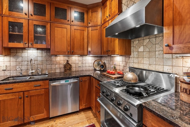 kitchen with sink, tasteful backsplash, extractor fan, appliances with stainless steel finishes, and dark stone countertops