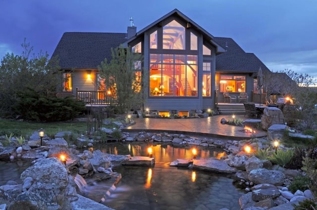 back house at dusk with a garden pond and a patio