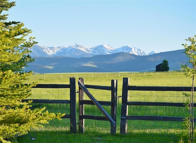 view of gate featuring a lawn, a mountain view, and a rural view