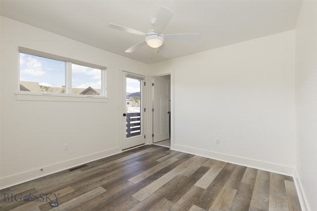 empty room featuring dark hardwood / wood-style floors, ceiling fan, and a wealth of natural light