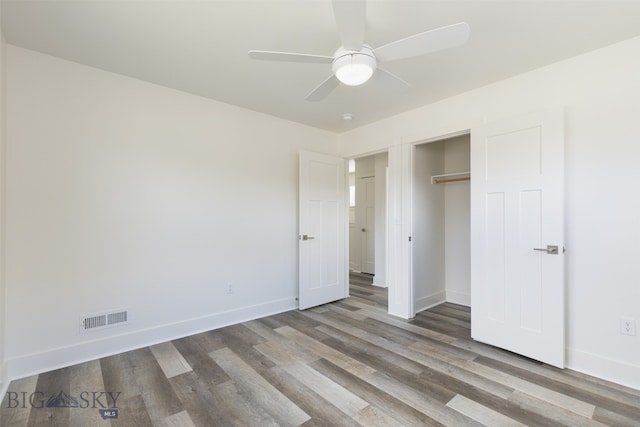 unfurnished bedroom with ceiling fan, wood-type flooring, and a closet