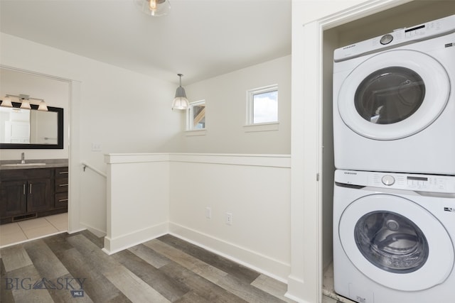 laundry area featuring sink, stacked washer / drying machine, and dark hardwood / wood-style floors