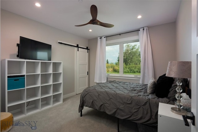 carpeted bedroom featuring a barn door and ceiling fan