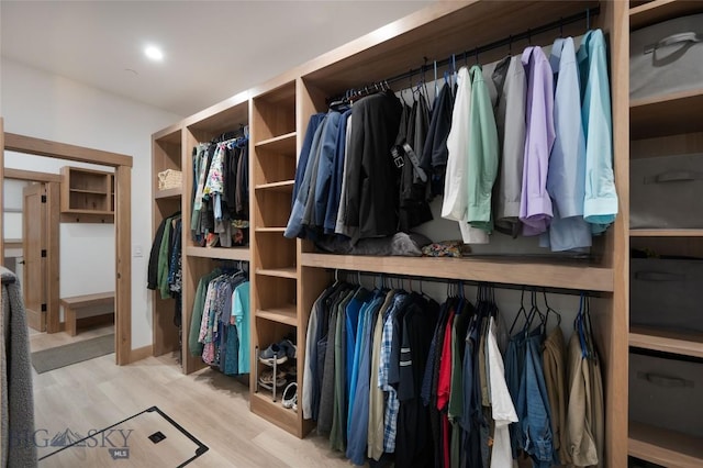 walk in closet with light hardwood / wood-style flooring