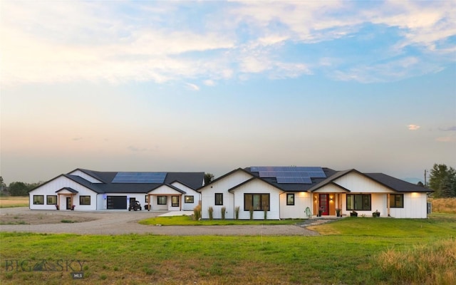 view of front facade featuring a lawn and solar panels