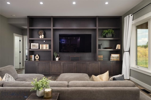 living room featuring wood-type flooring and built in features