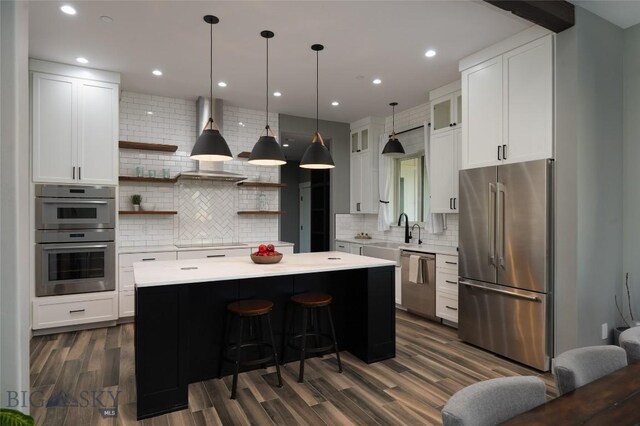 kitchen featuring pendant lighting, white cabinetry, stainless steel appliances, tasteful backsplash, and a kitchen island